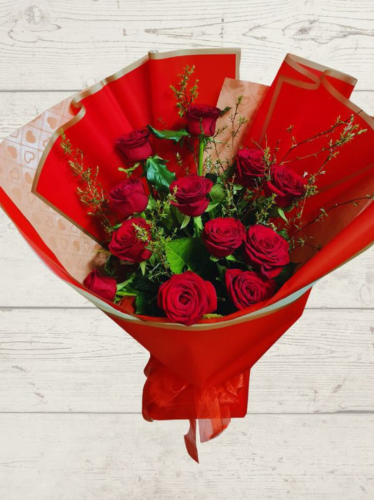 12 red roses with foliage wrapped in red and pink paper