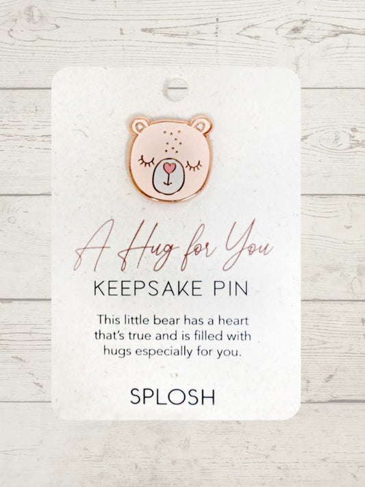 A rose gold keepsake pin with a bear face design and a textual message 'A Hug for You, Keepsake Pin' on a white cardboard backing.