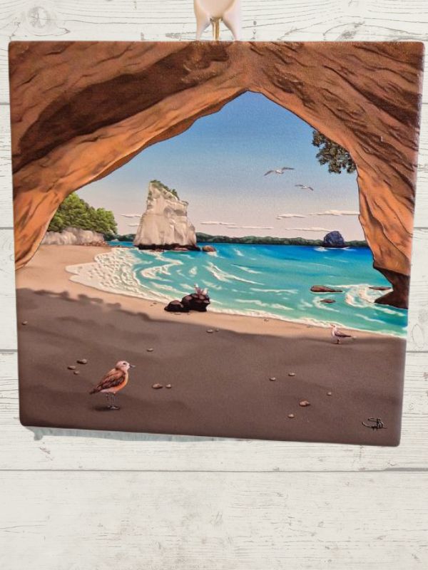 A ceramic tile featuring a vibrant scene with a beach, sea, and birds, framed by a brown border.