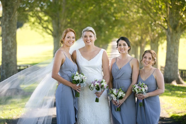 Bride with three bridesmaids holding lilac and white posy's at The red barn
