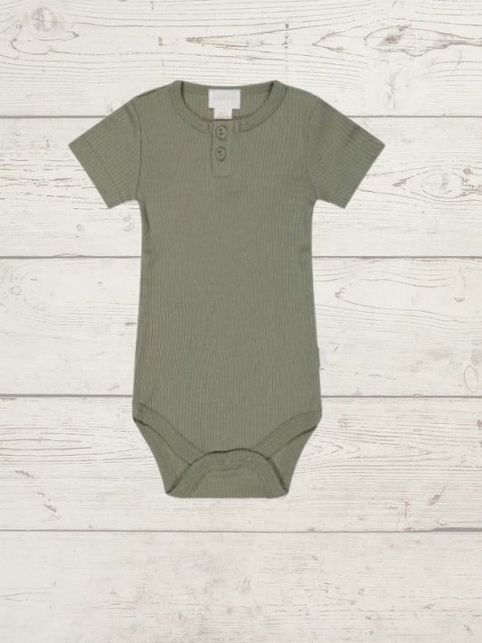 A green organic cotton modal darcy rib tee bodysuit for babies, displayed on a wooden background.