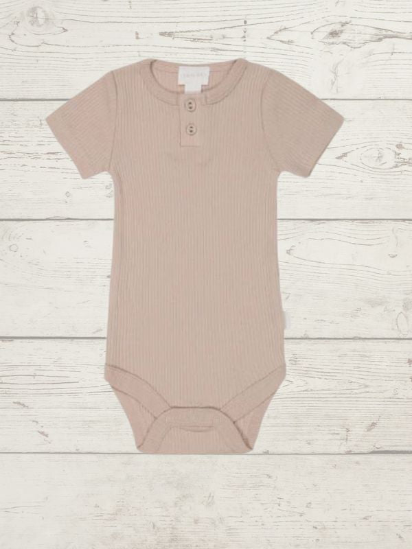 A rose organic cotton modal darcy rib tee bodysuit for babies, displayed on a wooden background.
