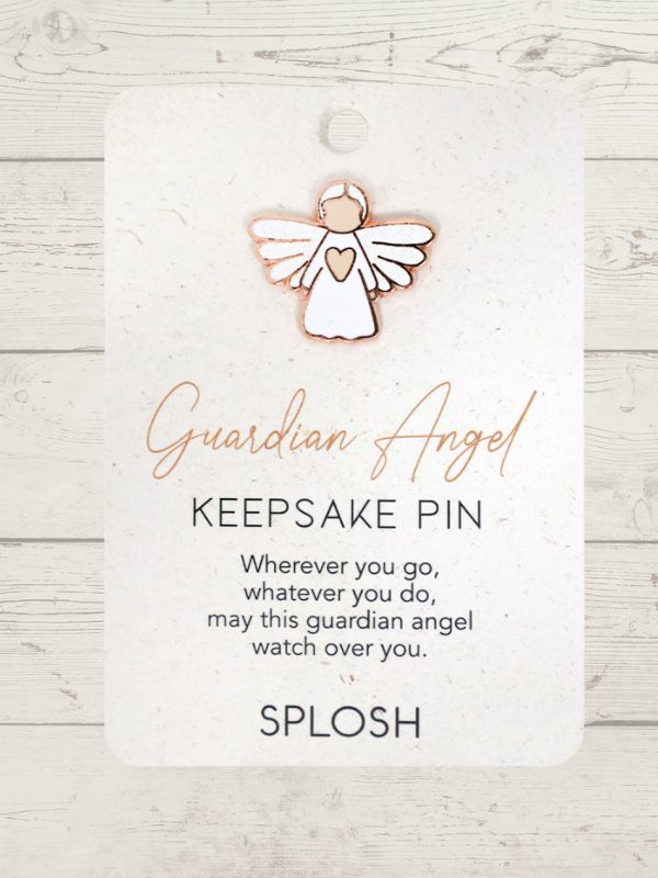 white guardian angel with a small pink heart keepsake pin on a card with a wooden background