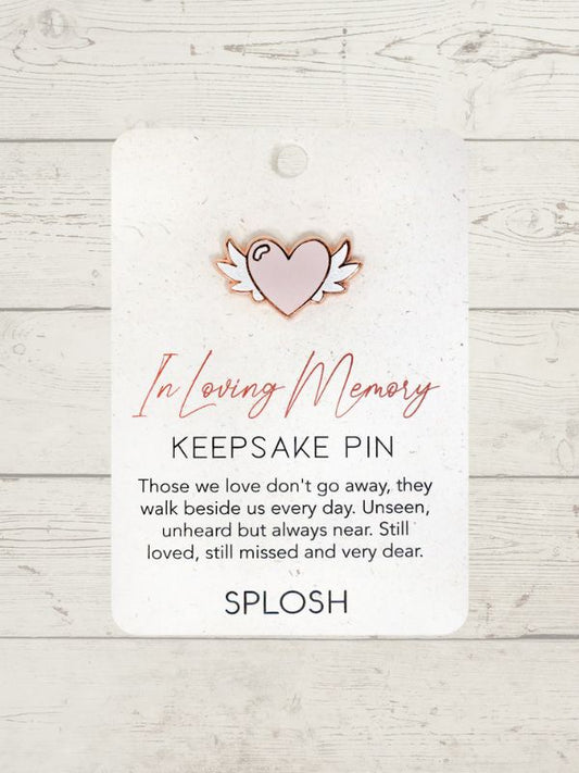 heart shape pin on a card with In loving memory written on it on a wooden surface