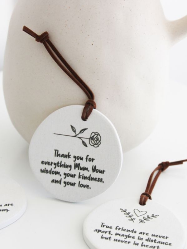A white ceramic keepsake with a rope, embossed with a quote about thanking one's mother for wisdom, kindness, and love.