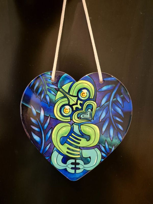 A ceramic heart with NZ tiki design in green with blue fern background
