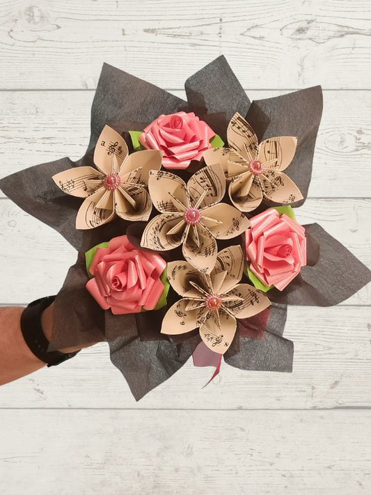 Bouquet of paper flowers with pink paper roses on a wooden background