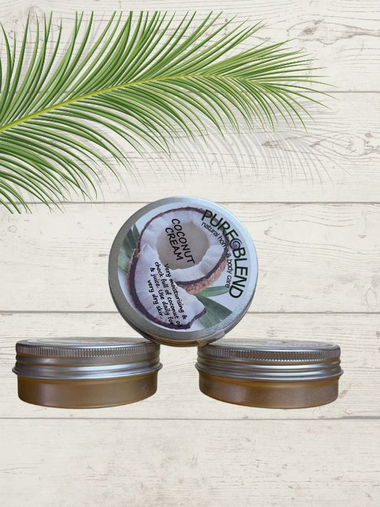 A tin of Pure blend coconut cream with its lid off, placed on a wooden surface with a palm leaf in the background.