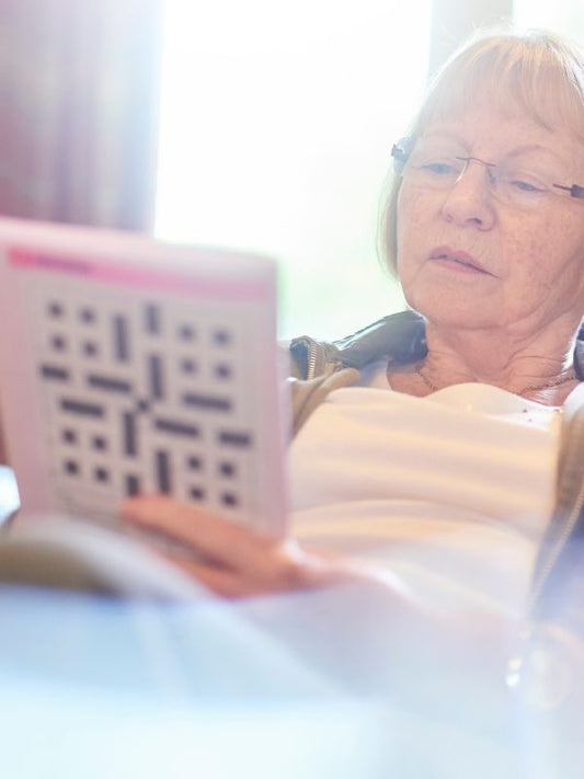 lady in a white tshirt and glasses looking at a crossword book