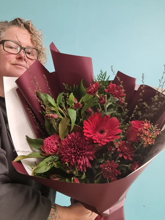 Person holding a bouquet of red flowers against a light blue background