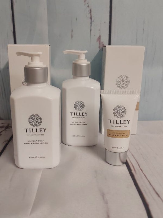 A Tilley branded gift pack containing a body wash, body lotion, and hand cream, displayed on a wooden surface with a blue background.