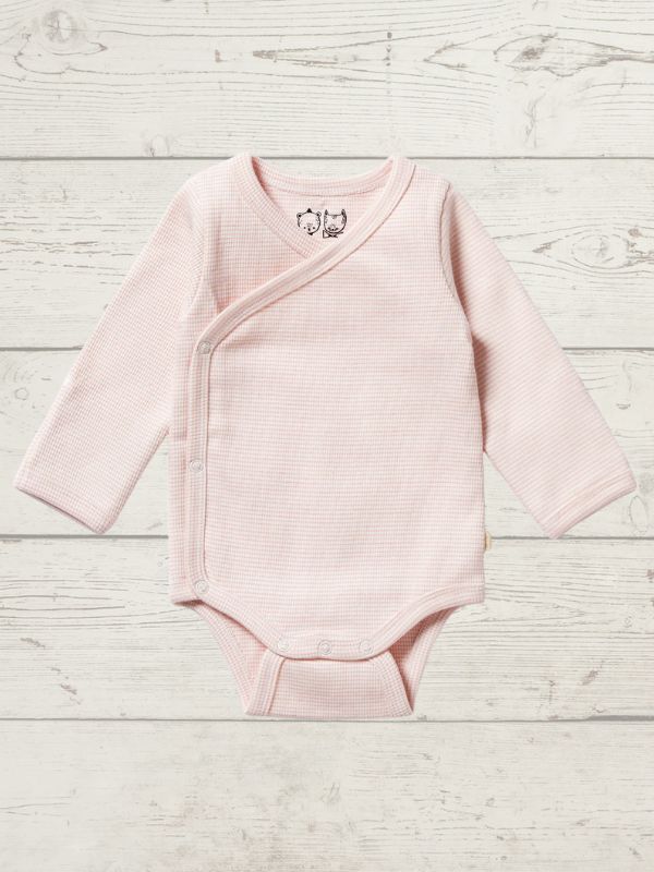 A pink long sleeve rib kimono bodysuit for babies, with a cross-over neckline and snap opening, displayed on a wooden background.