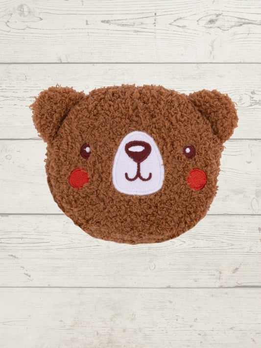 Brown teddy bear-shaped cushion on a light wooden surface