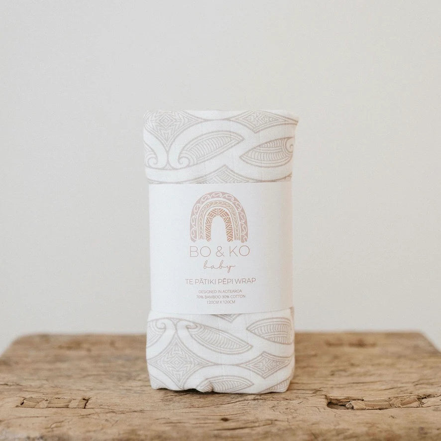White baby wrap with intricate patterns on a wooden surface
