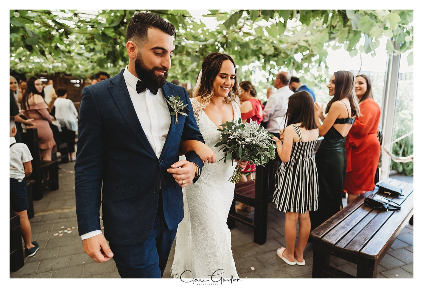 Wedding couple walking down the aisle with guests in the background.