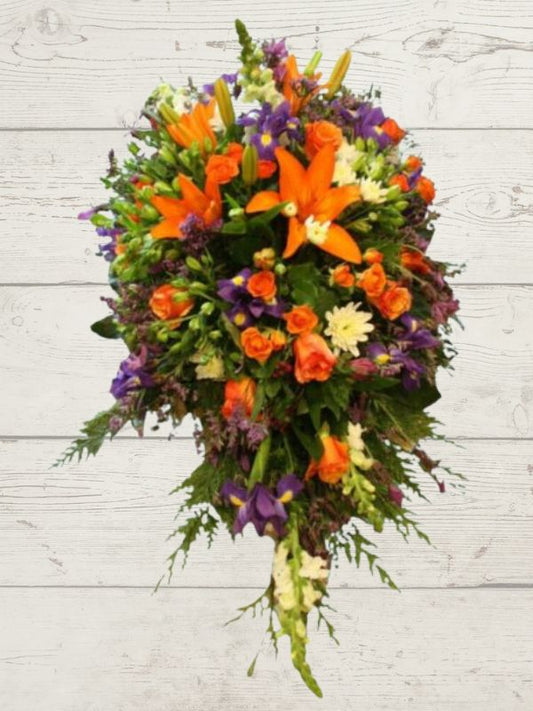 Floral tribute for funeral bright florals on white wooden background.