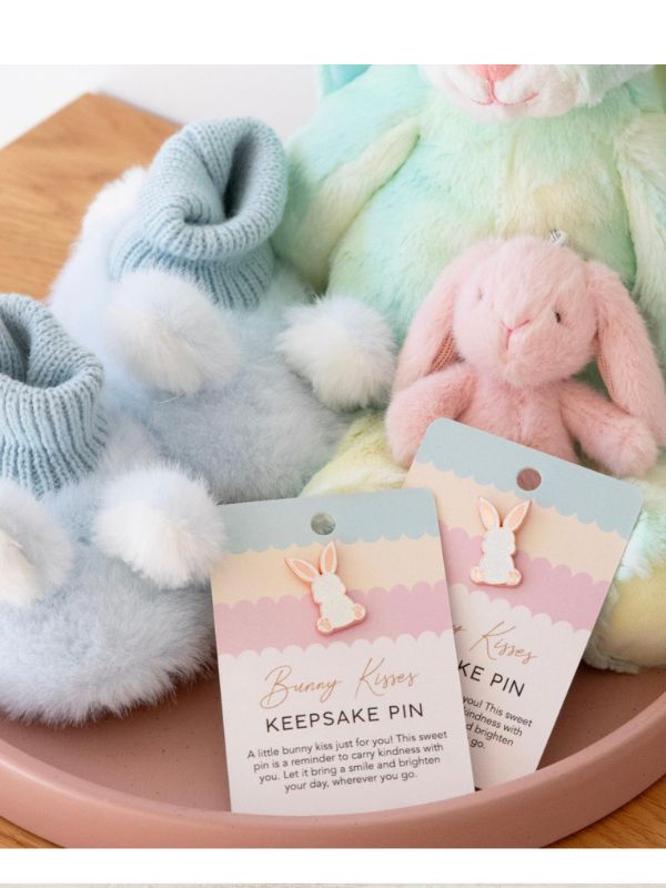 Bunny-shaped keepsake pins with packaging on a wooden surface