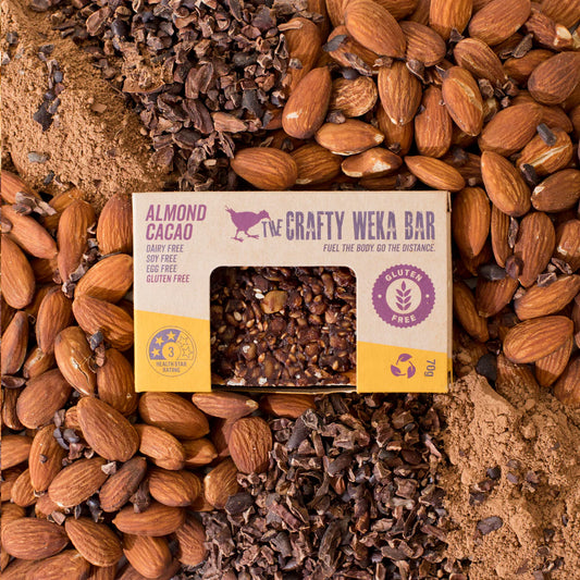 The Crafty Weka Bar almond cacao bar surrounded by almonds and cacao nibs.