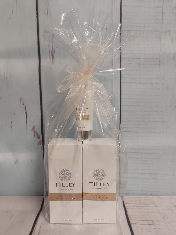 Tilley gift pack containing a body lotion, body wash and hand cream, gift wrapped on a white wooden background