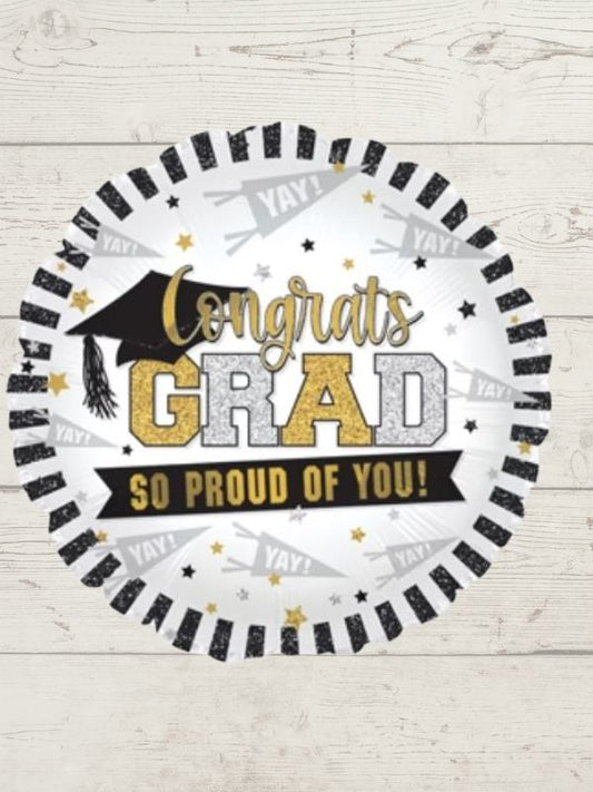 A round balloon with a 'Congratulations Graduate' message, featuring a graduation cap and stars, placed against a wooden background.