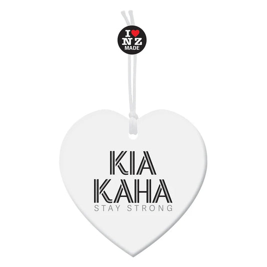 A white heart-shaped hanging ornament with the words 'KIA KAHA' and 'STAY STRONG' printed in black, plus a small circular 'I ❤️ NZ MADE' tag above it on a white background.