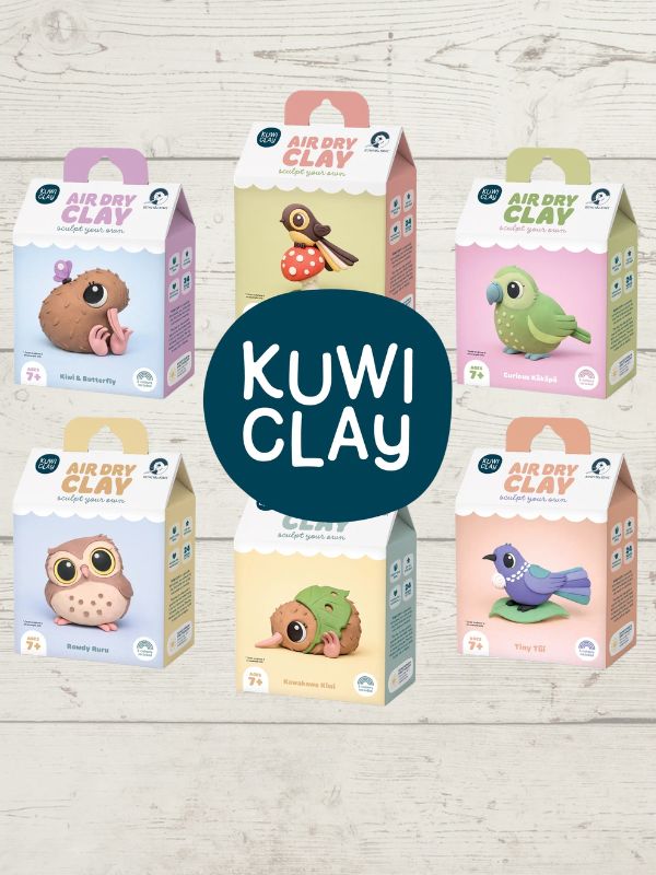 Six colorful boxes of Kuwi Clay air dry clay kits arranged on a light wood background, with a large dark blue circle in the center reading 'KUWI CLAY'. The boxes feature different animal illustrations including a pink creature, a brown bird, a green parrot, an owl, a turtle, and a bird.