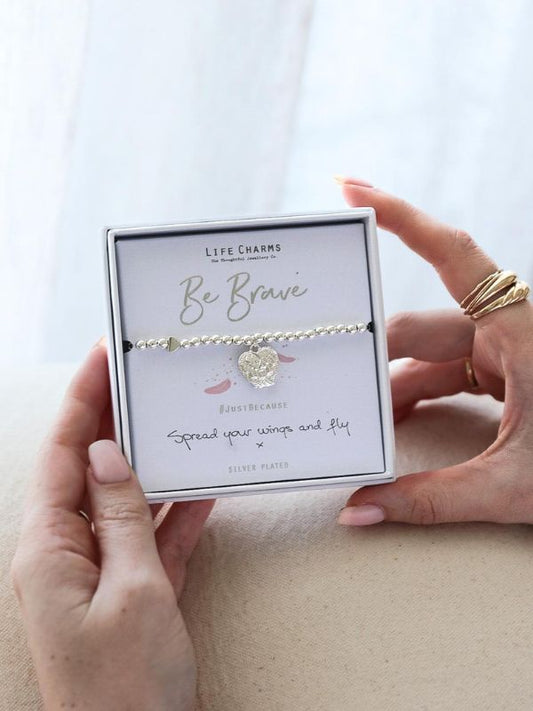 Bracelet with 'Be Brave' message in a Life Charms box held by hands.