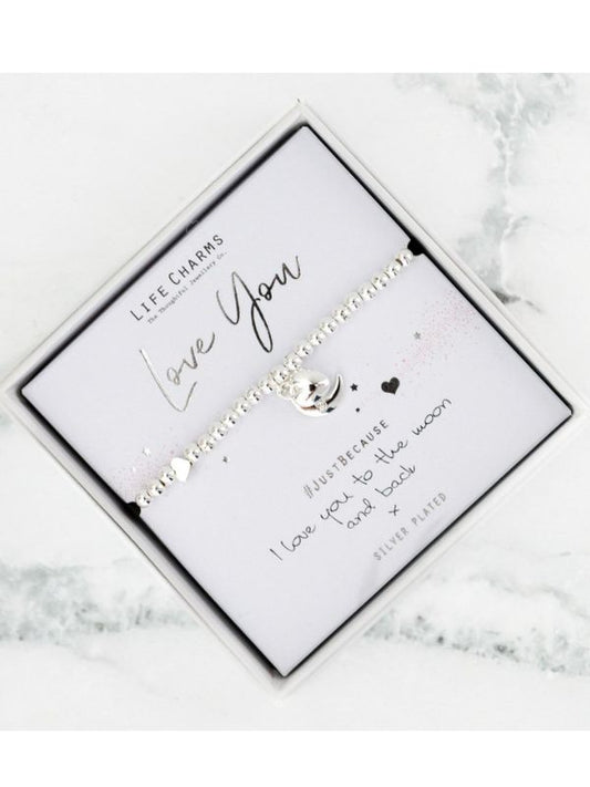 Silver bracelet with engraved message on a white card, placed on a marble surface.