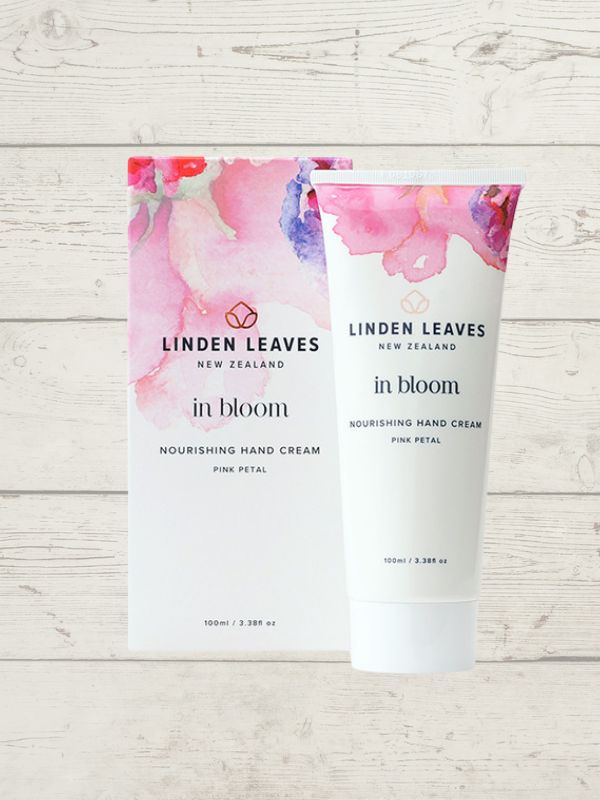 Linden Leaves In Bloom Nourishing Hand Cream packaging and tube, with a floral design and the product name visible, displayed on a wooden surface.