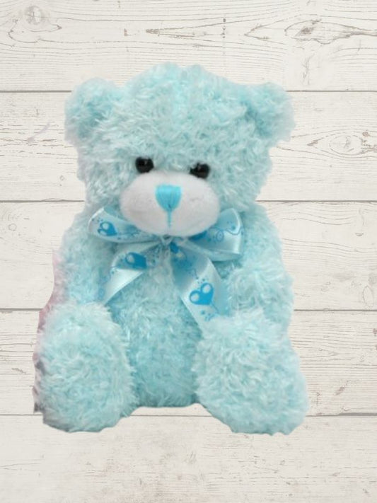 A blue plush teddy bear with a soft texture, standing against a wooden background.