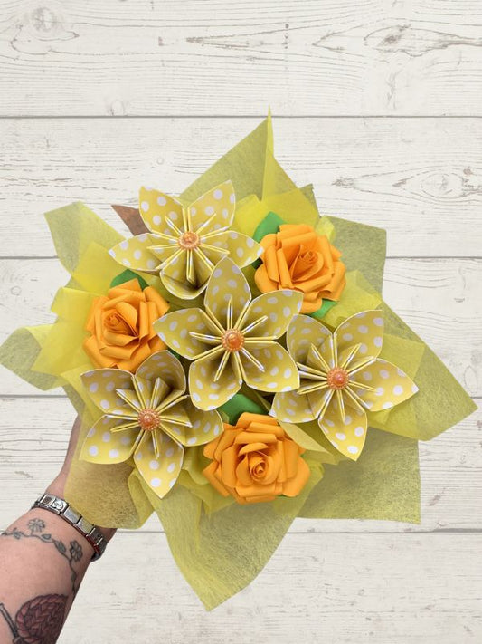 Bouquet of yellow and orange paper flowers on a wooden surface
