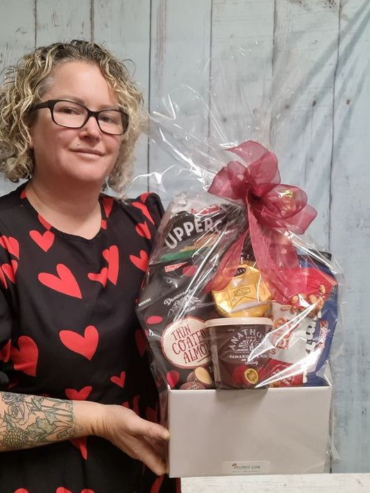 A hamper of mixed nibble food giftwrapped with ribbon.