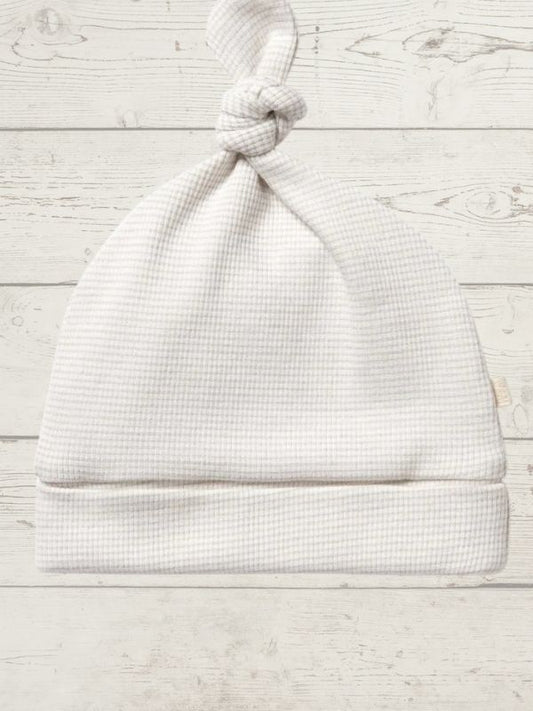 White baby hat on a light wooden surface