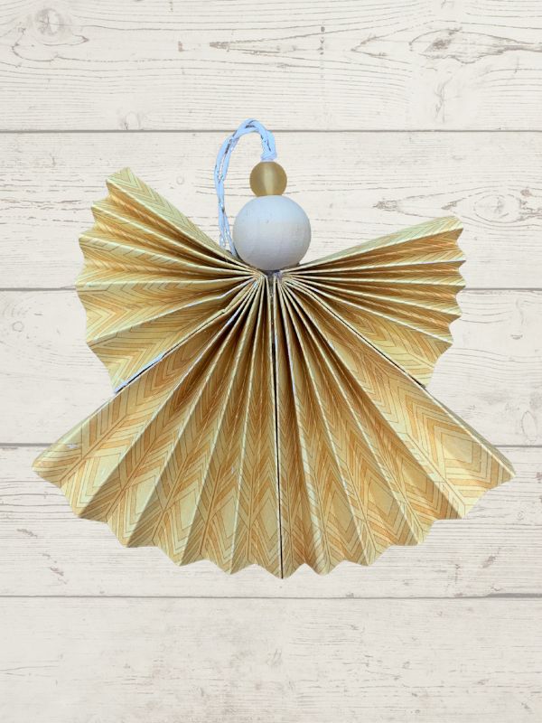 Decorative angel made from folded paper with a blue ribbon on a light wooden background
