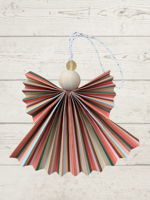 Decorative hanging item made from colorful paper with a wooden bead on a light wooden background