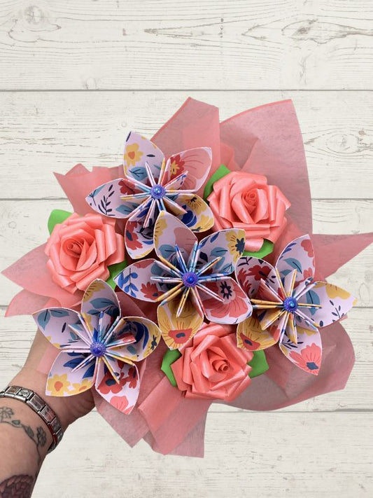 Bouquet of paper flowers and roses on a wooden surface