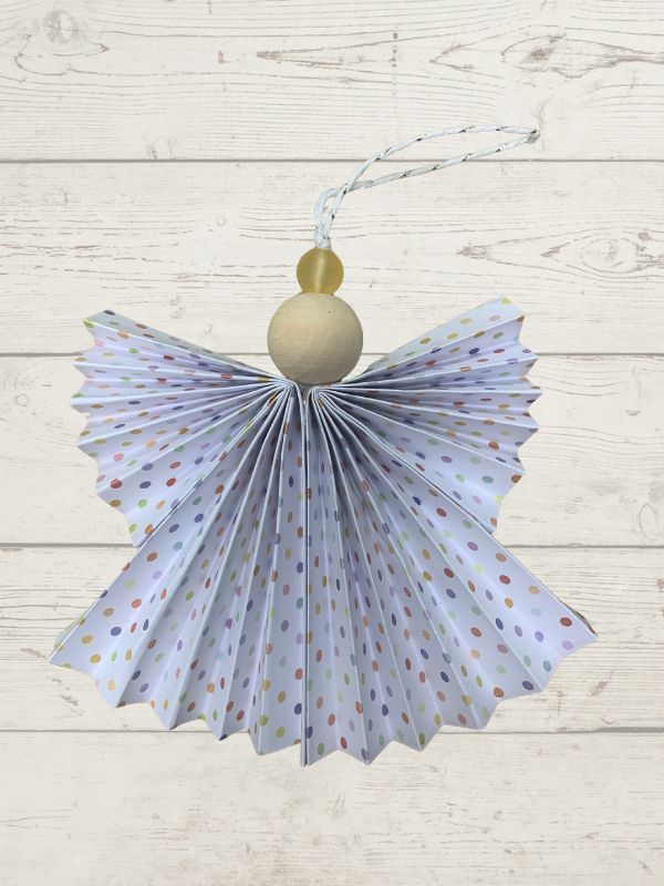 Decorative angel ornament with polka dot wings on a wooden surface