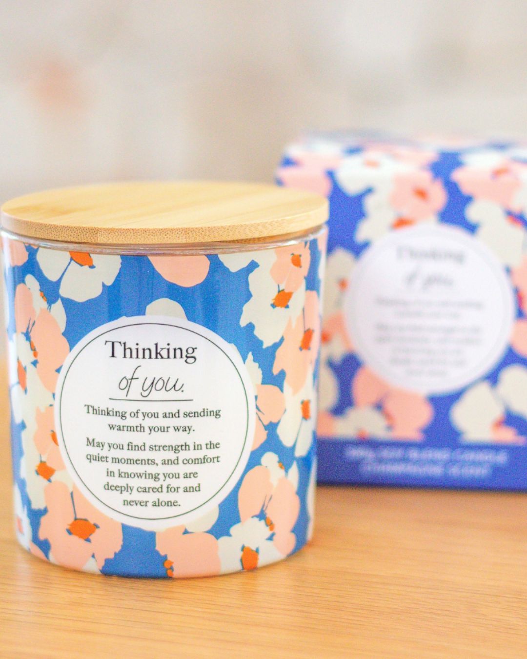 Floral-patterned candle with a wooden lid on a wooden surface, with a matching box in the background.