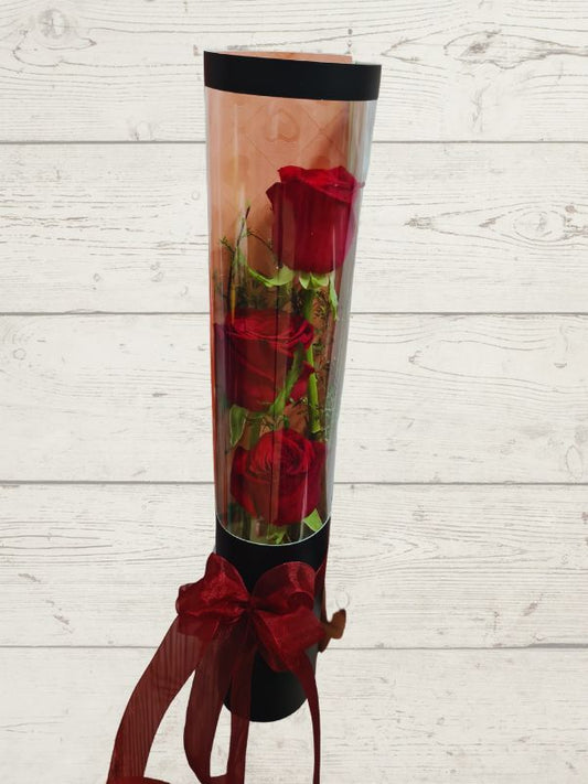 three red roses in black cylinder with red ribbon