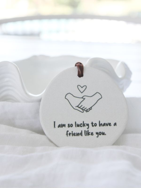 white ceramice decoration with holding hands and words on it on a white background