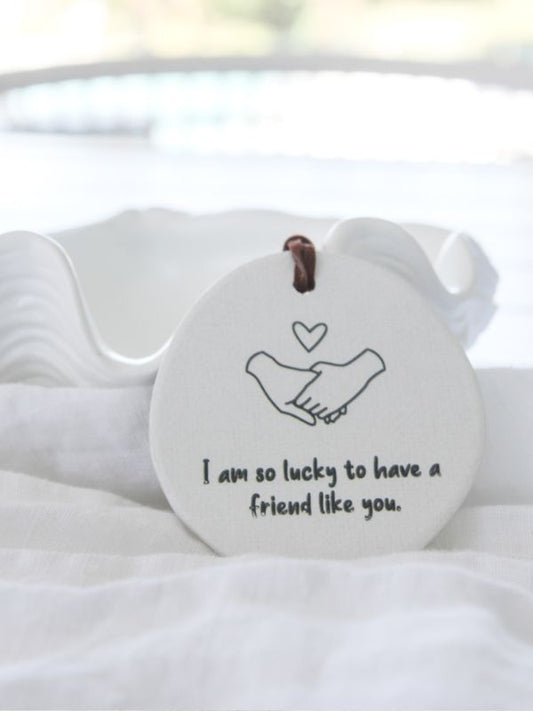 white ceramice decoration with holding hands and words on it on a white background