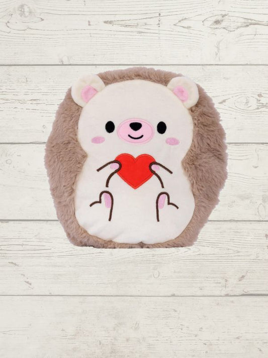 Plush toy resembling a bear with a red heart on a light wooden background