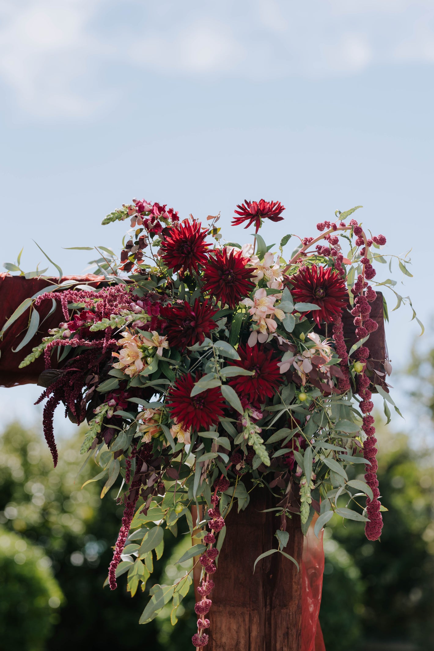 Decorative floral arrangement on wedding archway with red and green flowers on a blurred natural background