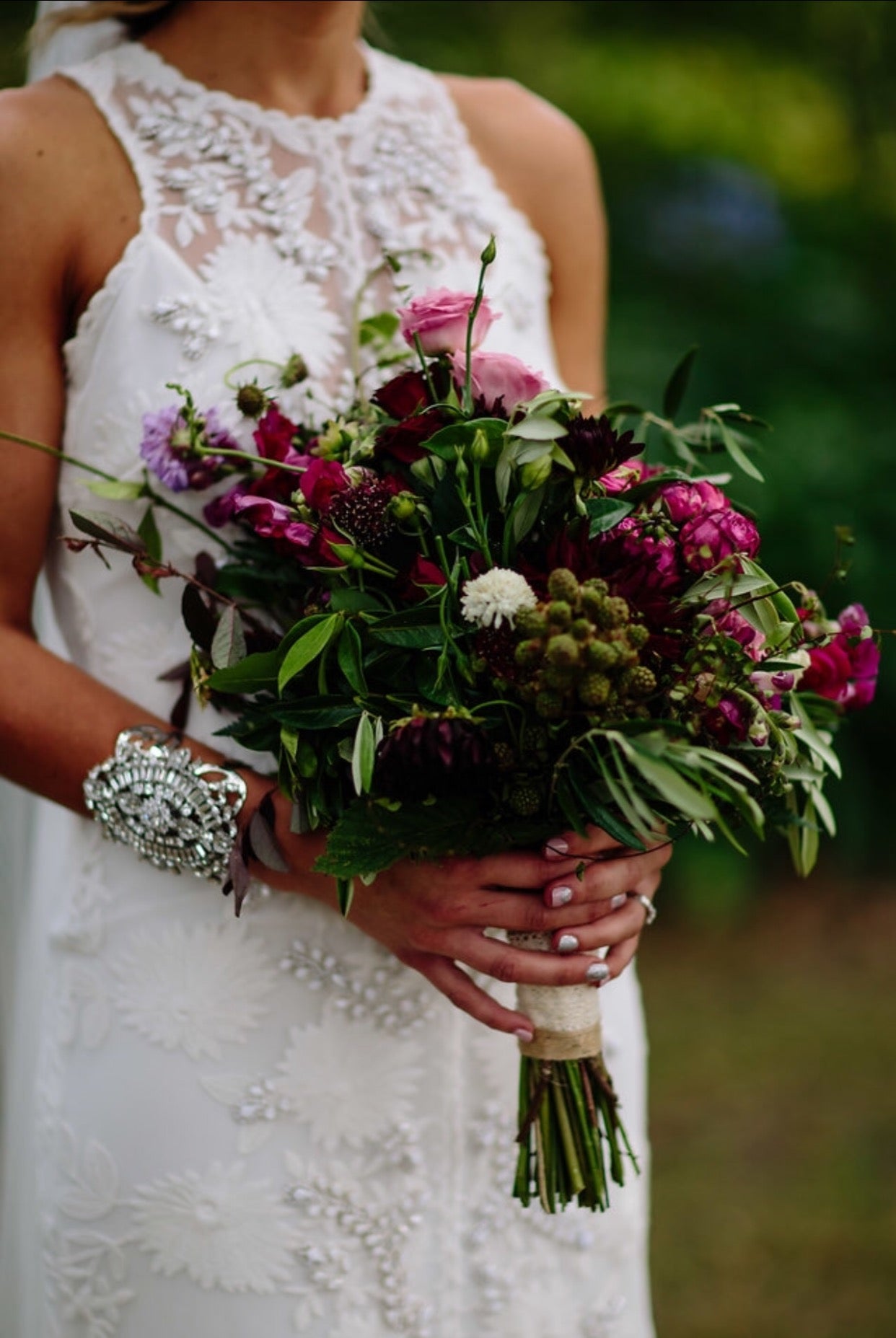 Bride holding a bouquet of flowers with a blurred green background