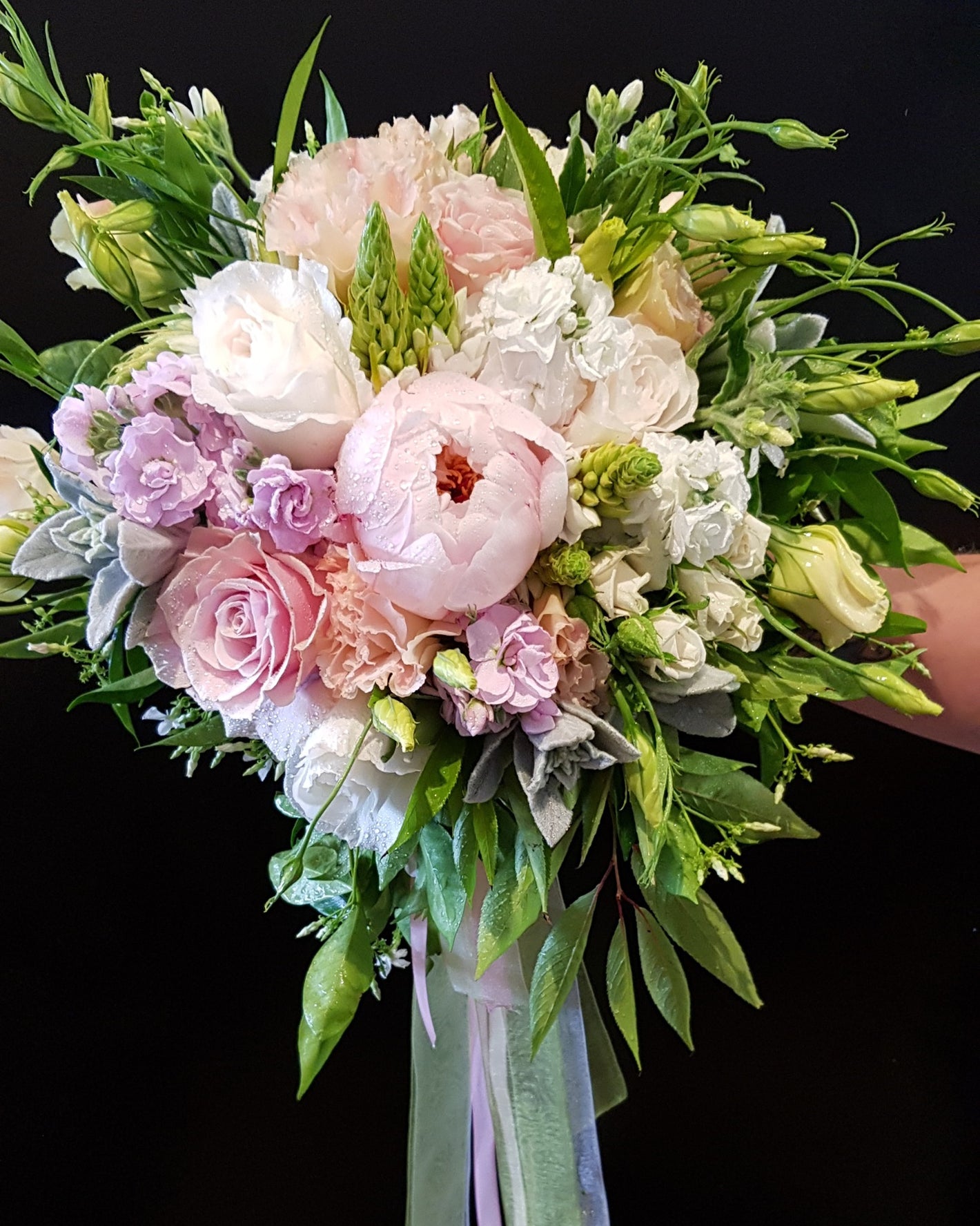 Wedding bouquet of flowers with pink, white, and green colors on a black background