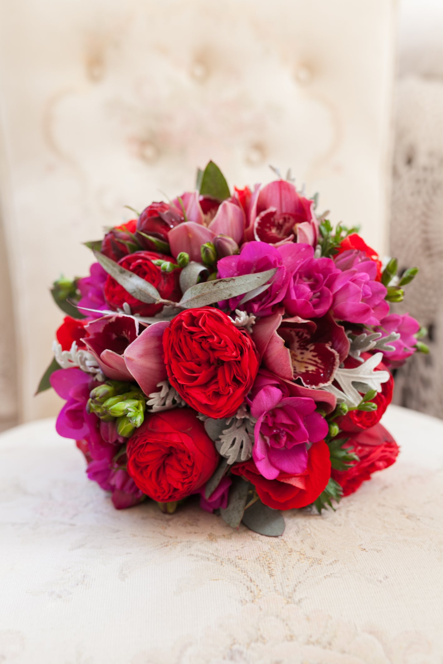 Bouquet of red and pink flowers on a white surface with a blurred background