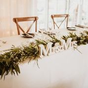 Decorated table with greenery and 'Memorial' sign, set against a white wall.