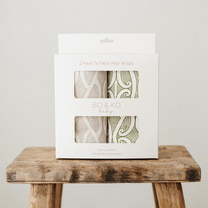 Pack of BO & KO baby wraps on a wooden stool with a plain background