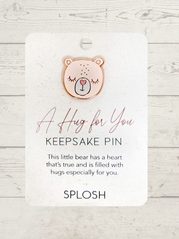 A rose gold keepsake pin with a bear face design and a textual message 'A Hug for You, Keepsake Pin' on a white cardboard backing.