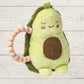 Plush avocado toy with a pink teething ring on a light wooden background